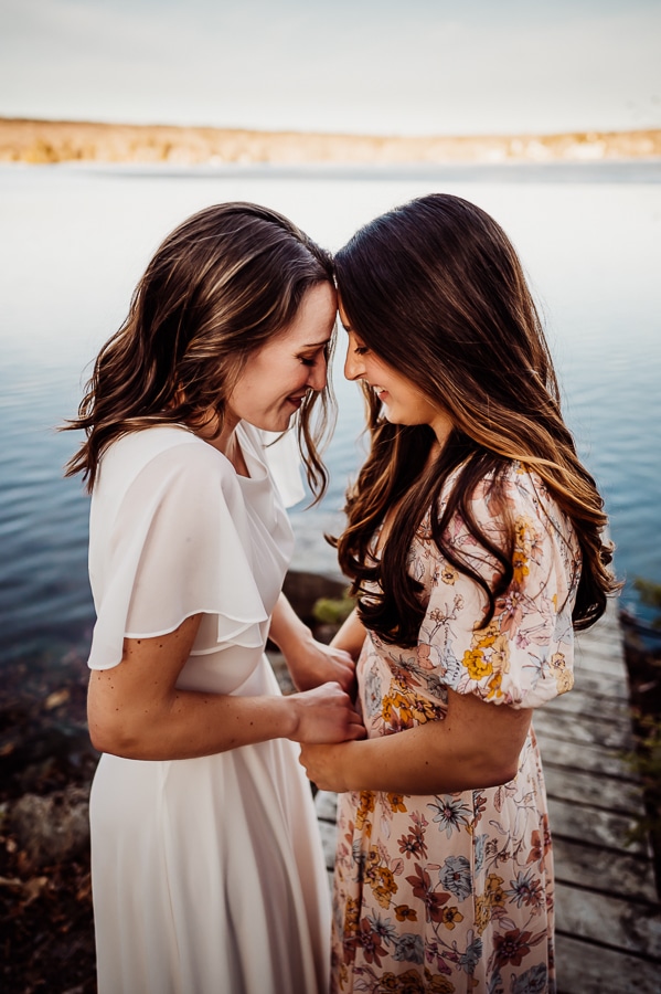 Two women facing each other in front of lake