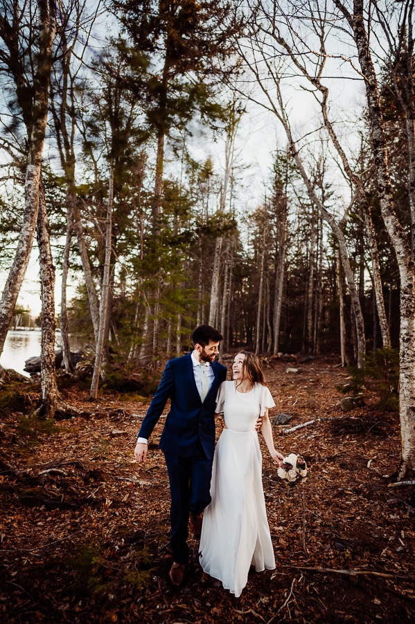 Bride and groom walking through the woods in maine