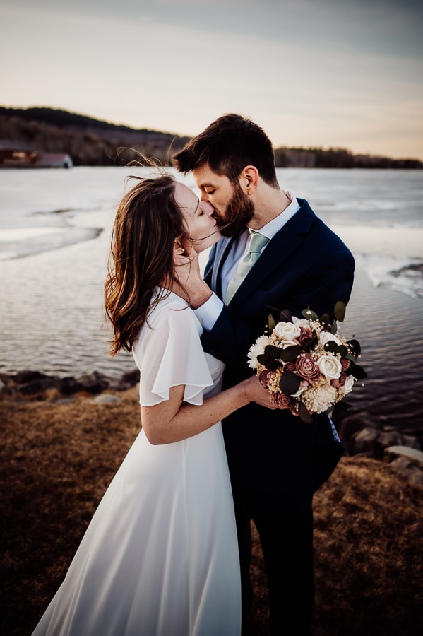 Bride and groom touching noses in front of moosehead lake