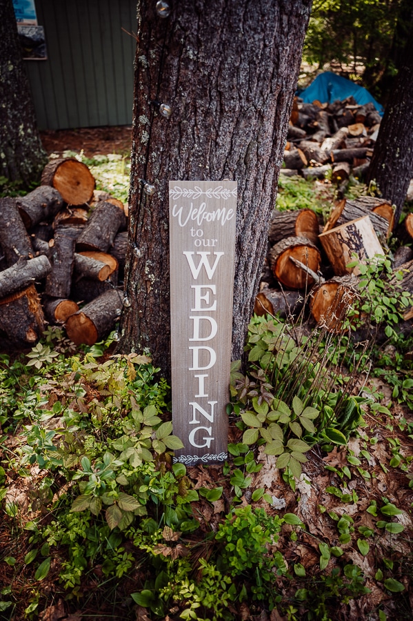 Wedding Welcome sign leaning against tree in the grass