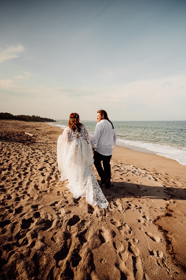 Bride and groom walking away from camera on old orchard beach