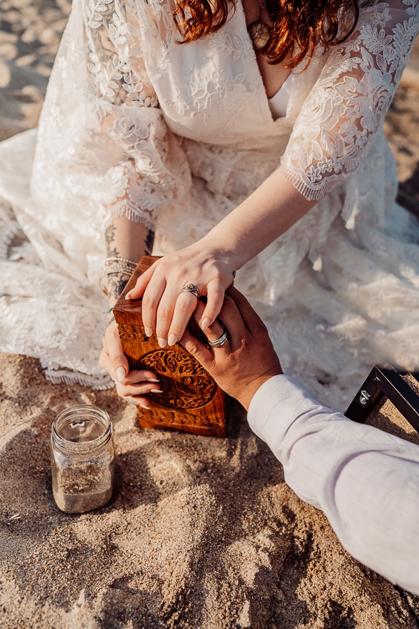 Bride and groom holding son's urn on the beach