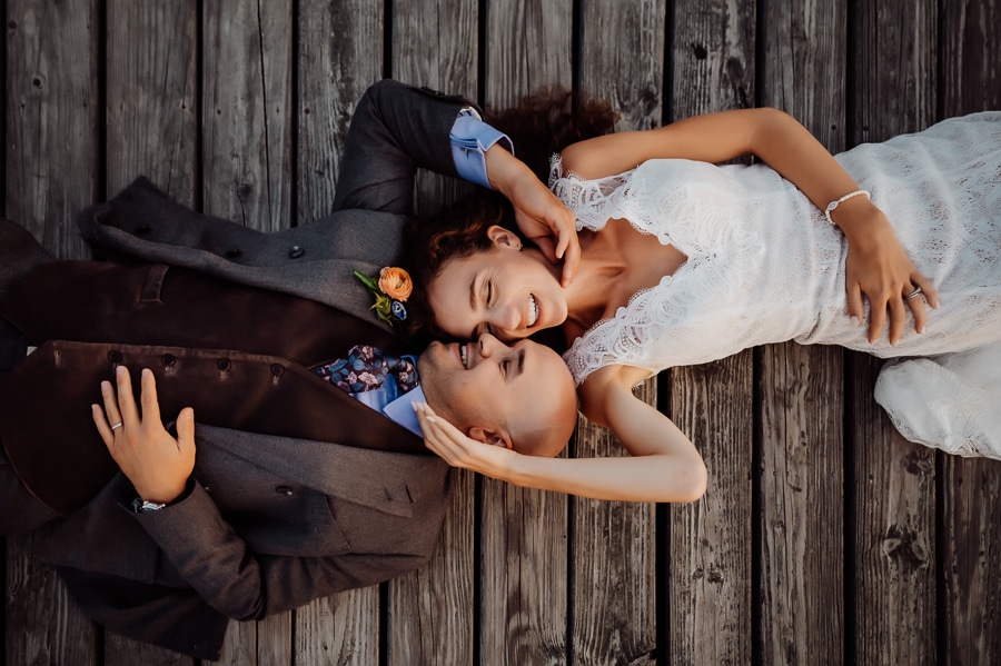 Bride and groom laying down on dock at big moose inn