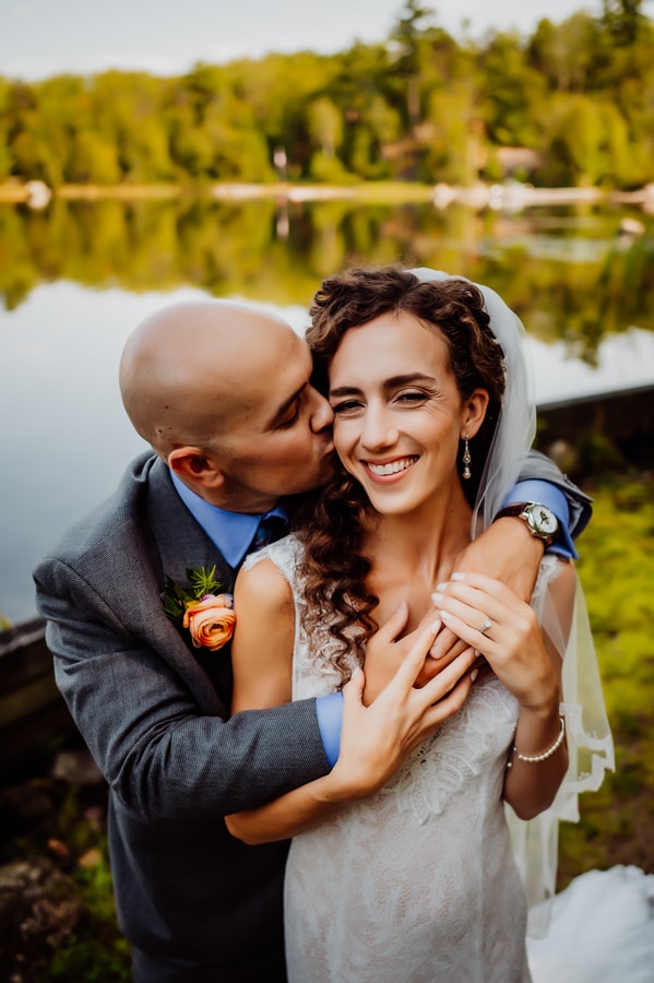 Bride and groom holding each other in front of millinocket lake