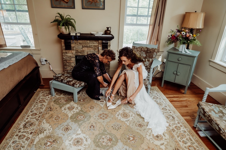 Mother helping bride put shoes on before wedding at big moose inn