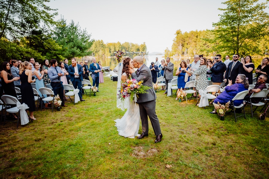 bride and groom kissing after ceremony in middle of isle at big moose inn