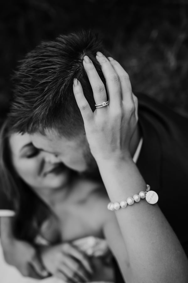 Womans hand on husbands head with wedding ring in focus