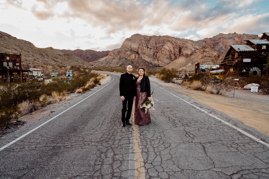 bride and groom holding hands walking in the middle of the road at nelson ghost town