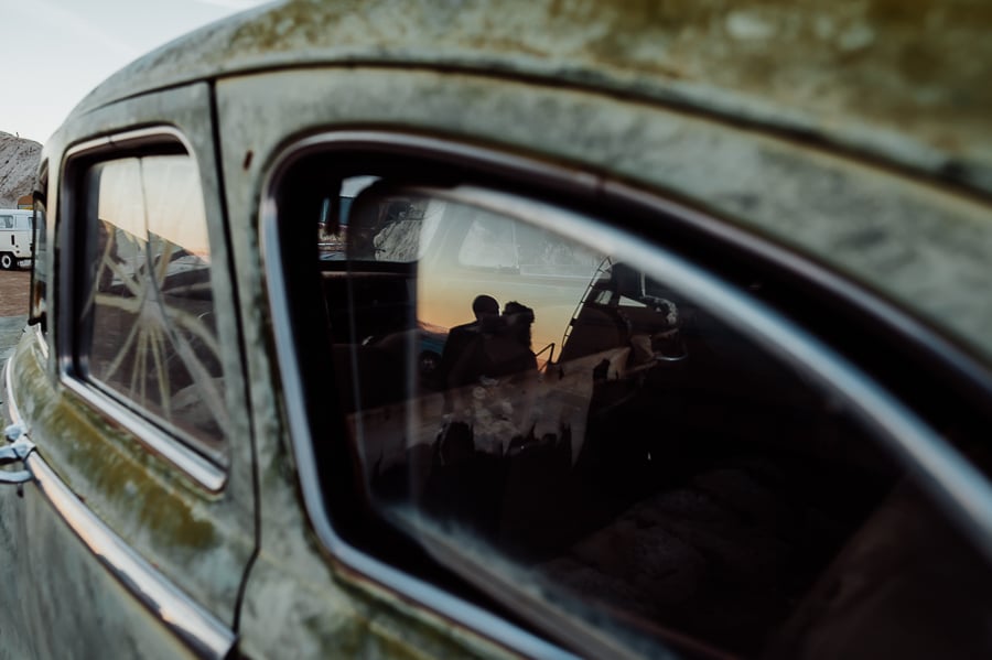 Bride and groom kissing in reflection of old antique car at nelson ghost town vegas