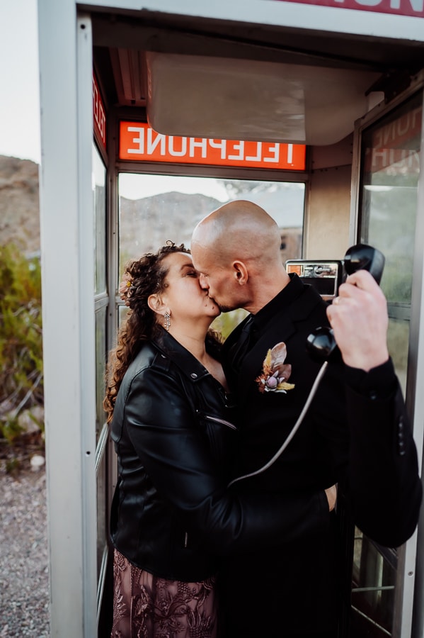 groom holding phone inside old phone booth kissing bride at nelson ghost town