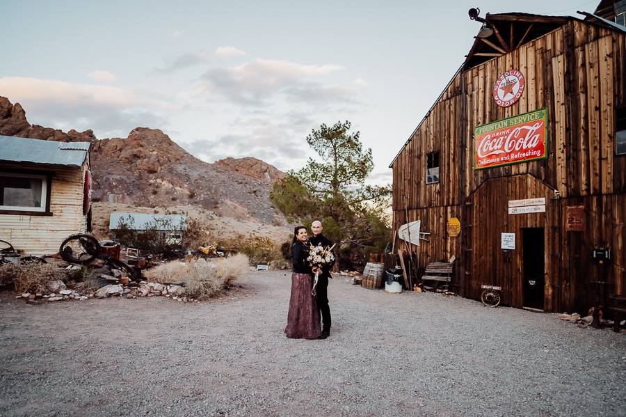 Bride and groom posing together at nelson ghost town in front of barn