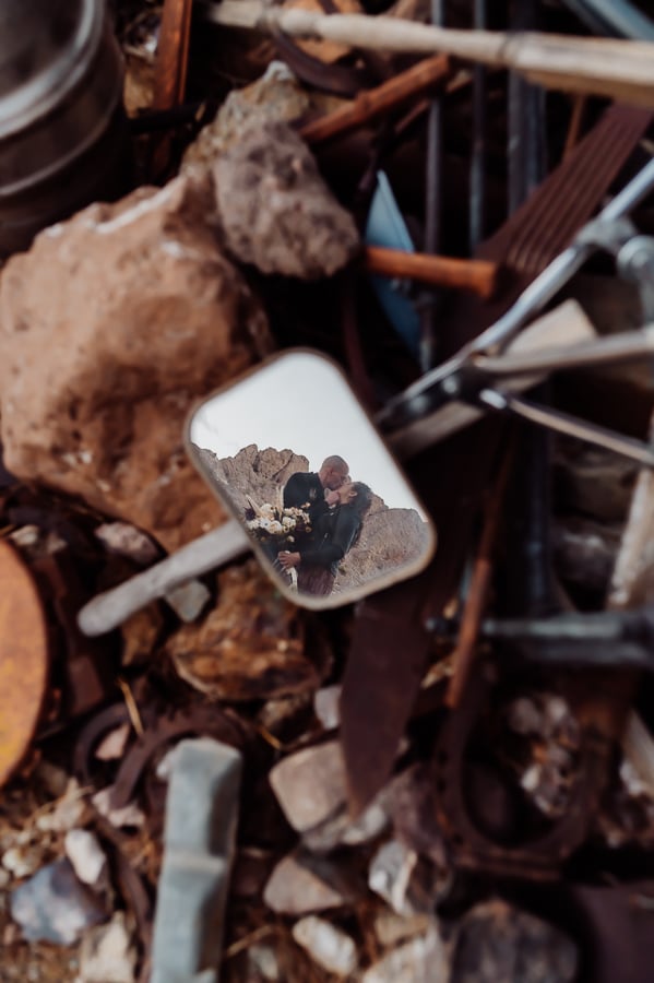 Bride and groom kissing in reflection of side mirror