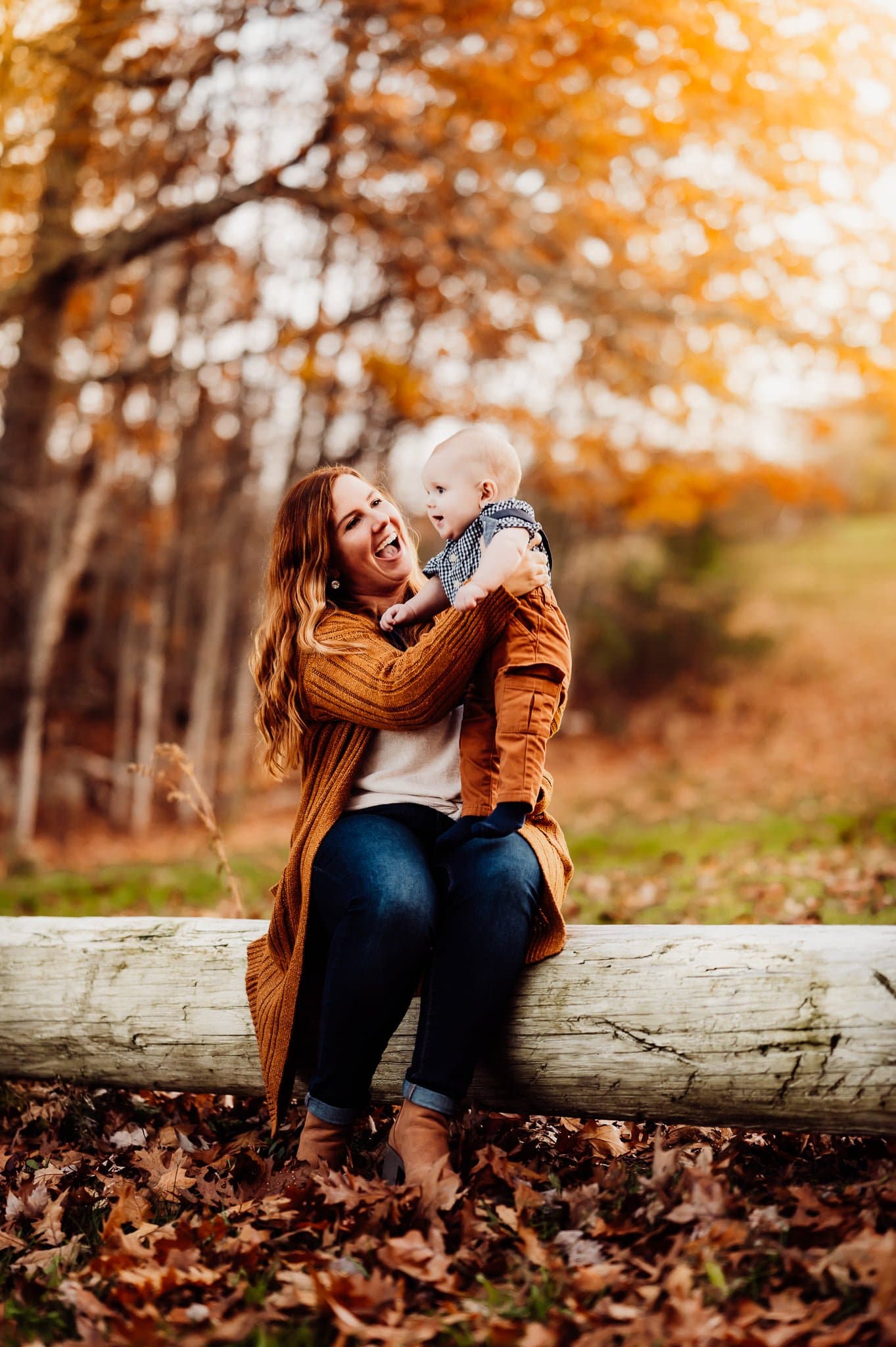mother and son sitting on log in the fall