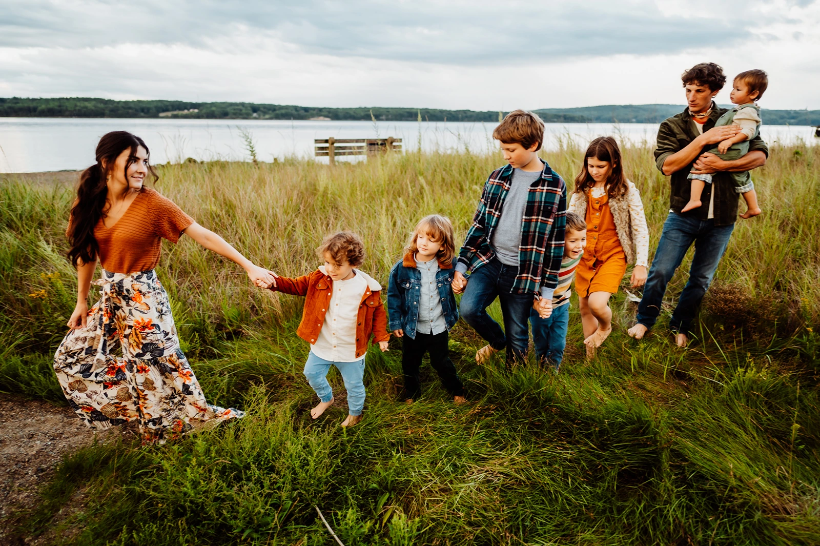 Big family of six walking through grass in front of beach