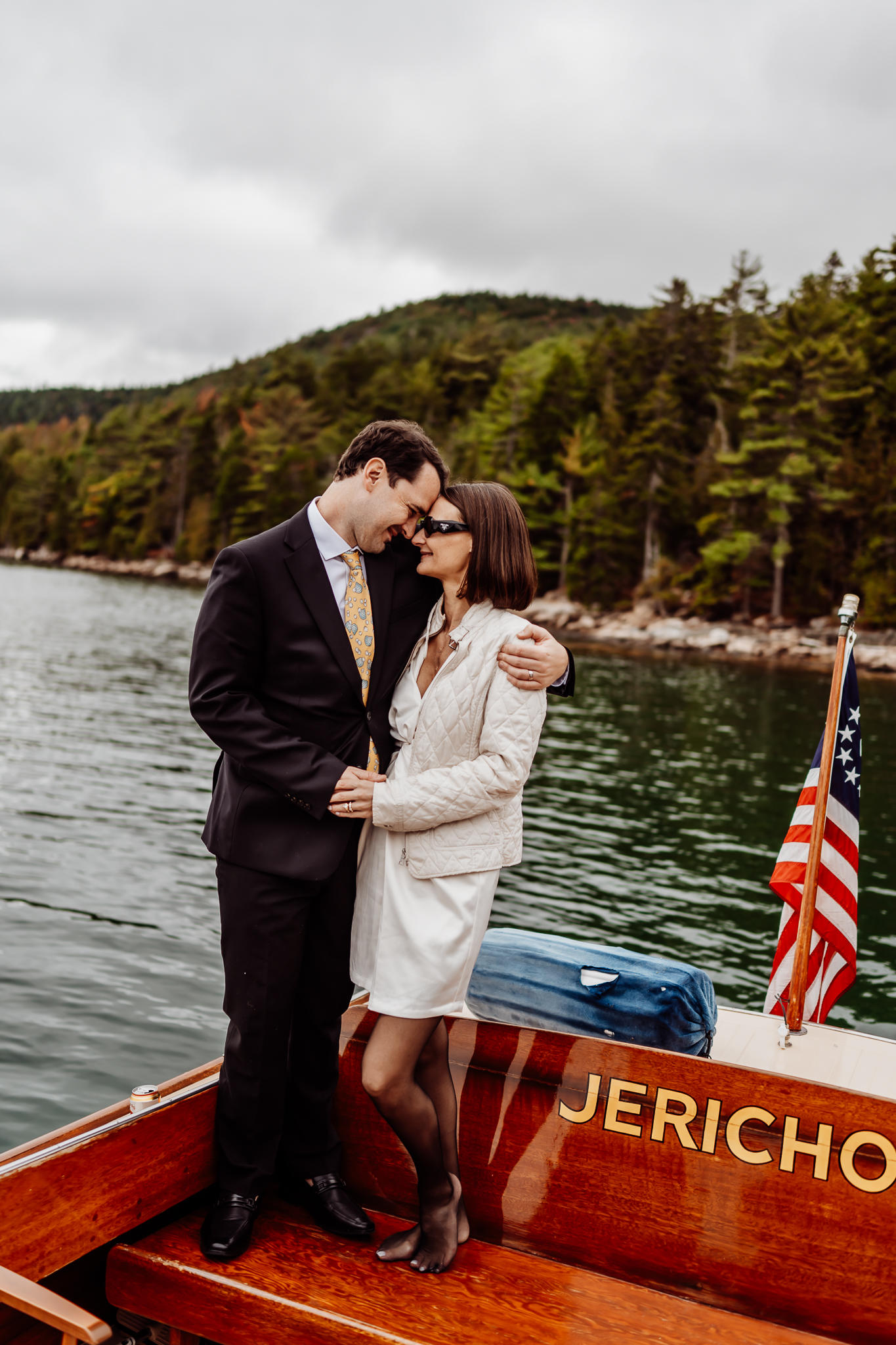 Bride and groom embracing each other on the back of a boat in Acadia