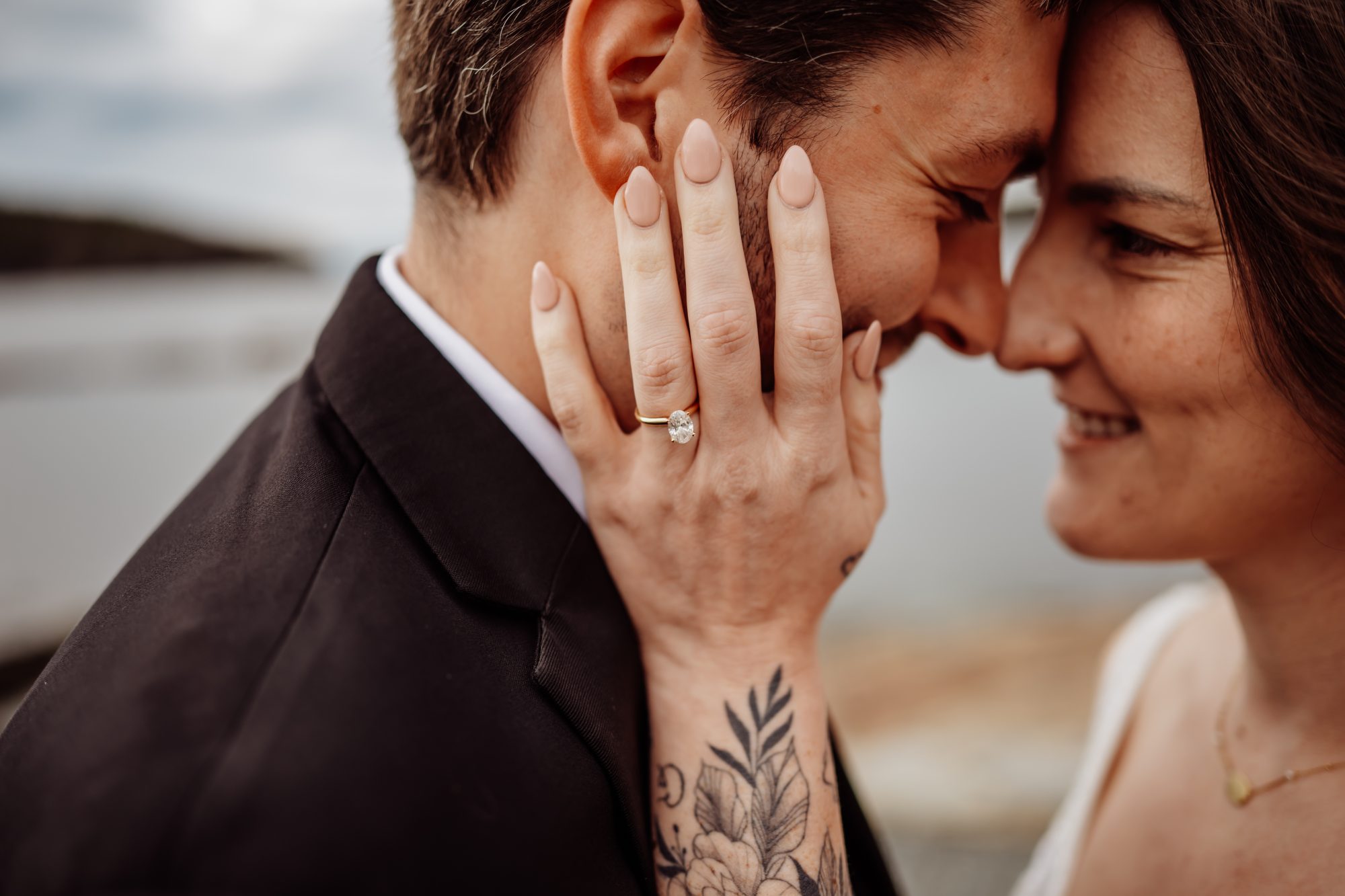 Close-up elopement detail photo featuring an engagement ring, intimate embrace, and emotional moment by the Maine coastline