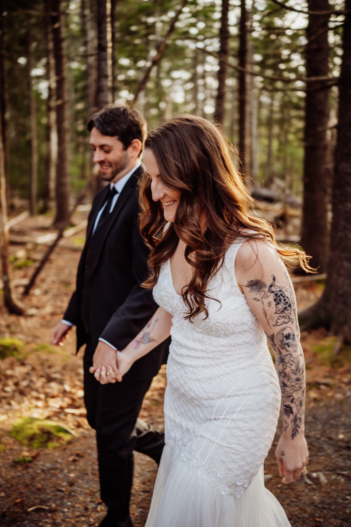 Couple holding hands while walking through the forest near Jordan Pond during an intimate Acadia elopement
