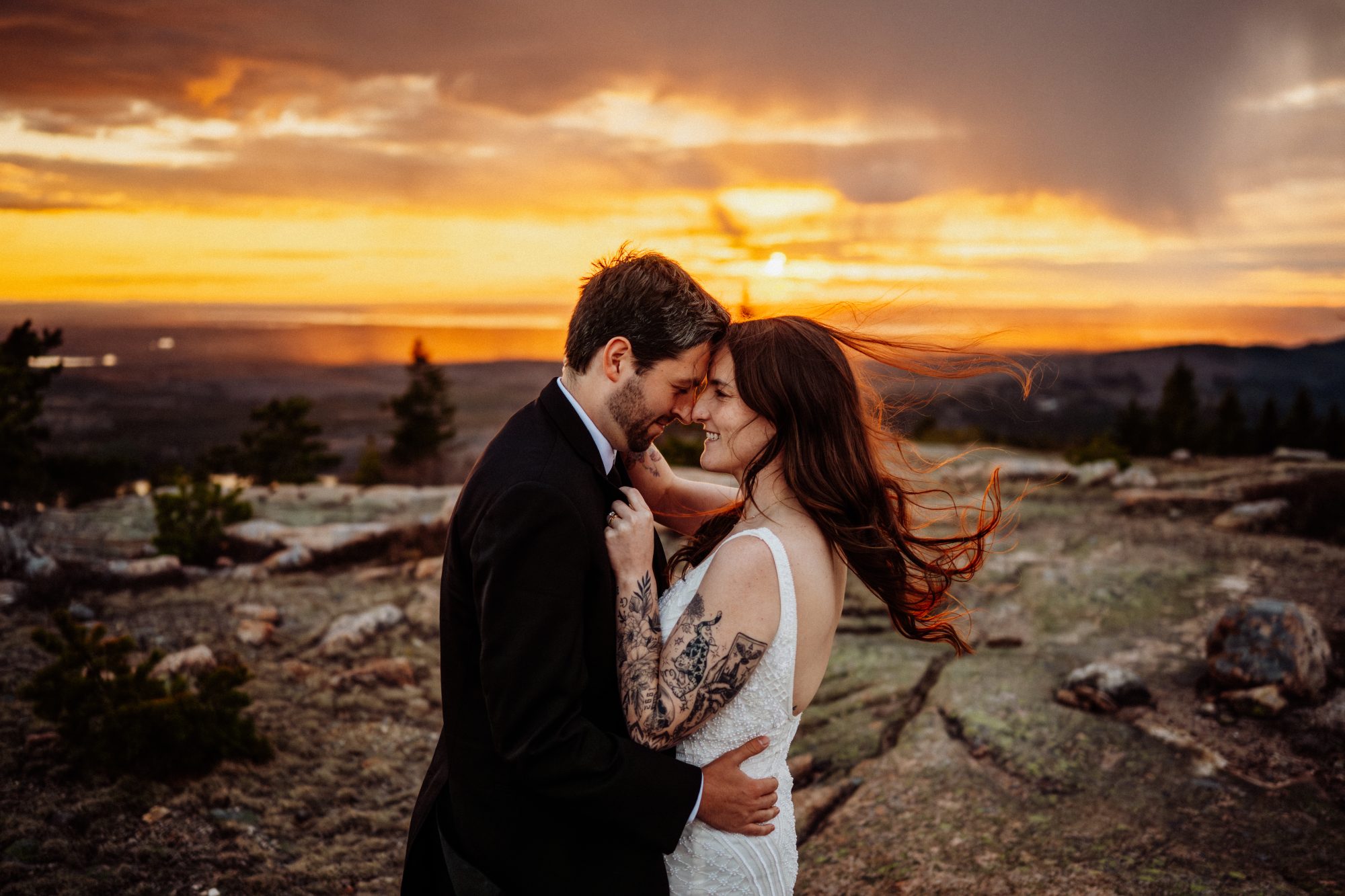 Romantic sunset portrait of an adventurous couple embracing on the rocky summit of Acadia National Park, Maine