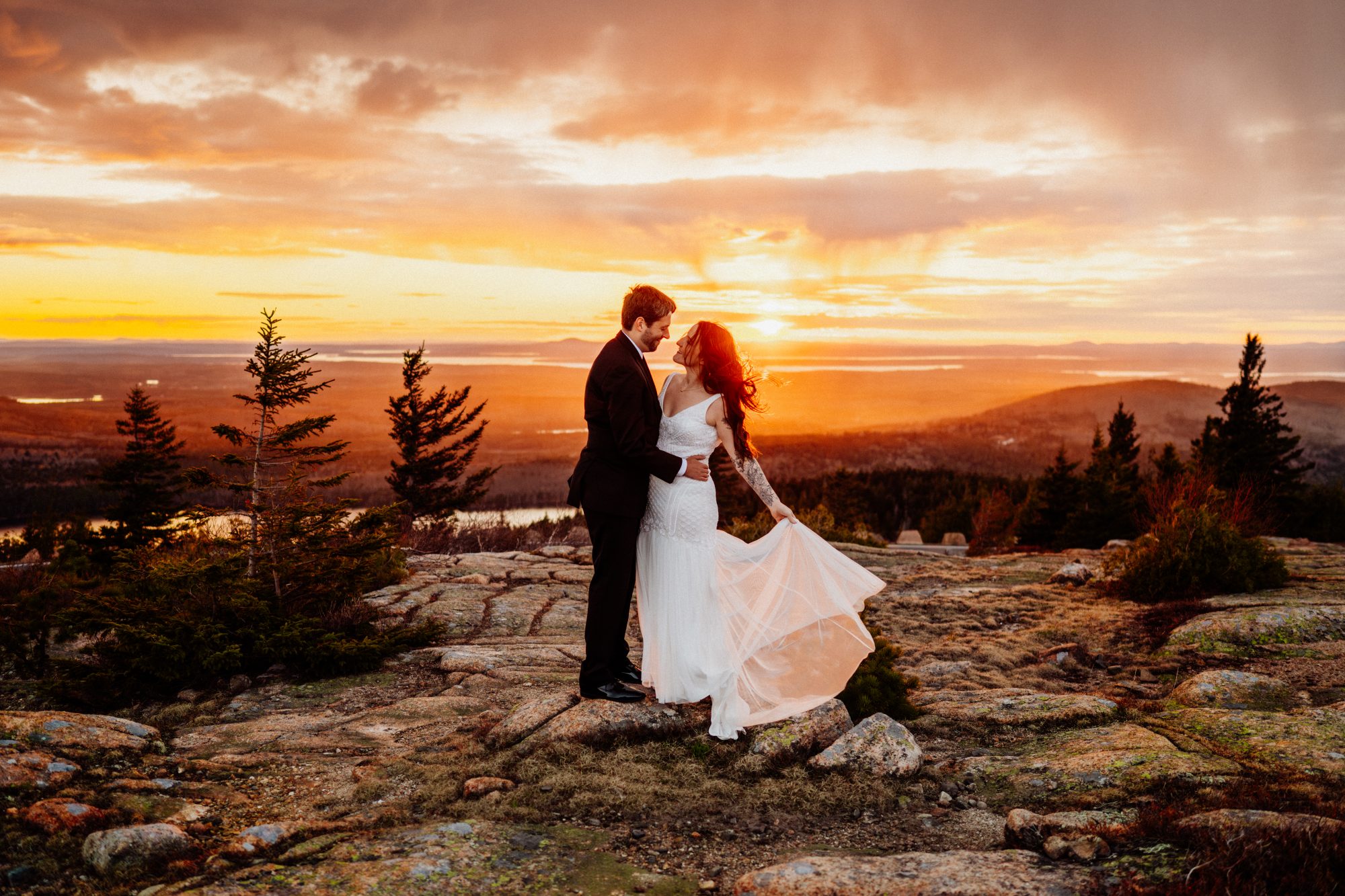Bride and groom standing together on rocky cliffs during a golden hour elopement in Acadia National Park, Maine